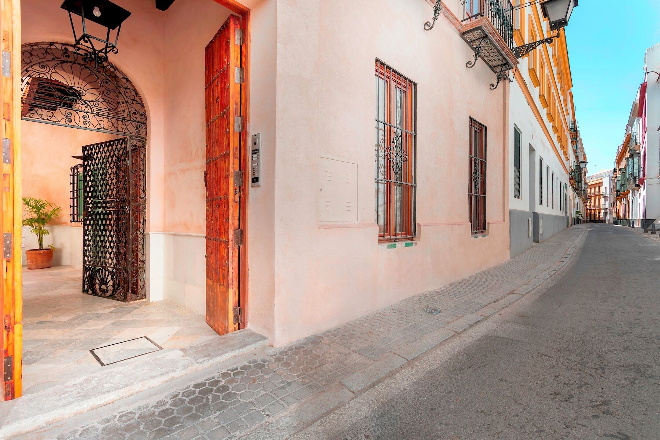 Une rue étroite bordée d’immeubles à l’architecture traditionnelle, avec une porte en bois et un pot de fleurs.