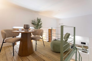 Eine moderne Küche mit einem Holztisch, Stühlen, einem grünen Pouf und einer eingebauten Mikrowelle.