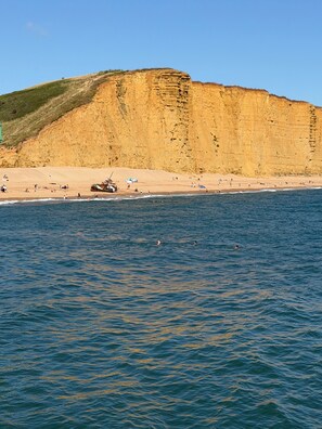 A coastal beach with cliffs, sandy shore, and calm sea.