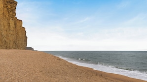 A coastal landscape with a sandy beach and a cliff. - The Chalet Self Contained With Patio (Bridport)