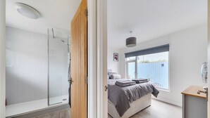 A modern bedroom with a shower, a bed with a view of the outside, and a balcony. - The Chalet Self Contained With Patio (Bridport)