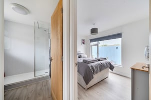 A modern bedroom with a shower, a bed with a view of the outside, and a balcony.