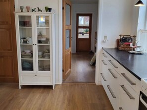 Eine Küche mit weißen Schränken, Holzboden und einer Arbeitsplatte mit Korb und Wasserkocher.