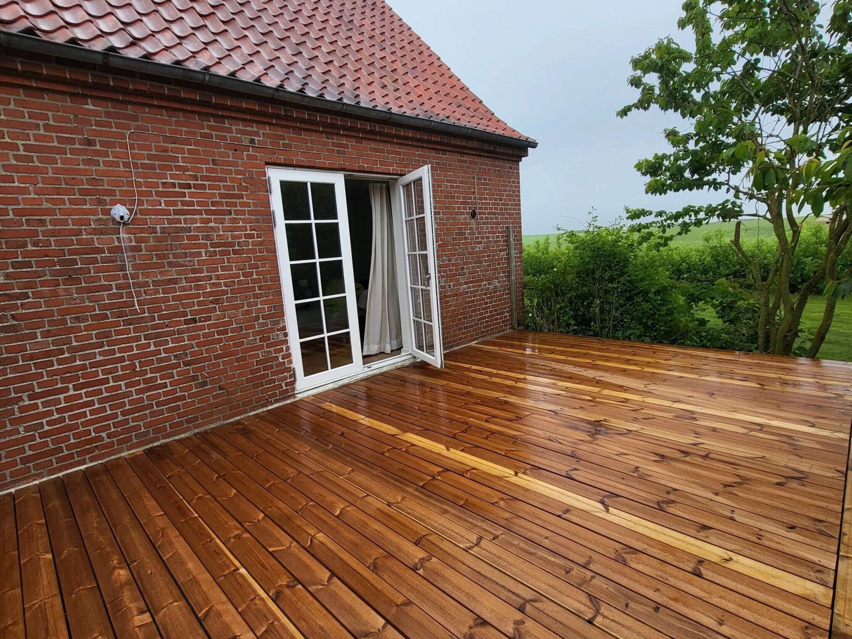 A brick building with a wooden deck and a door leading to a covered outdoor area.