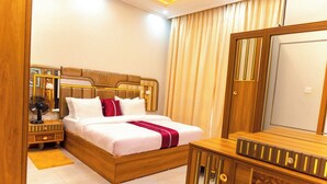 Ein Hotelzimmer mit einem hölzernen Bett, einem großen Spiegel, einer Holzkommode und einem Nachttisch mit Lampe.