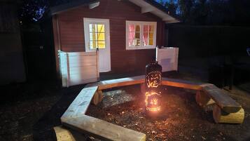 Een houten vakantiehuis met veranda, een bankje en een brandende lantaarn.