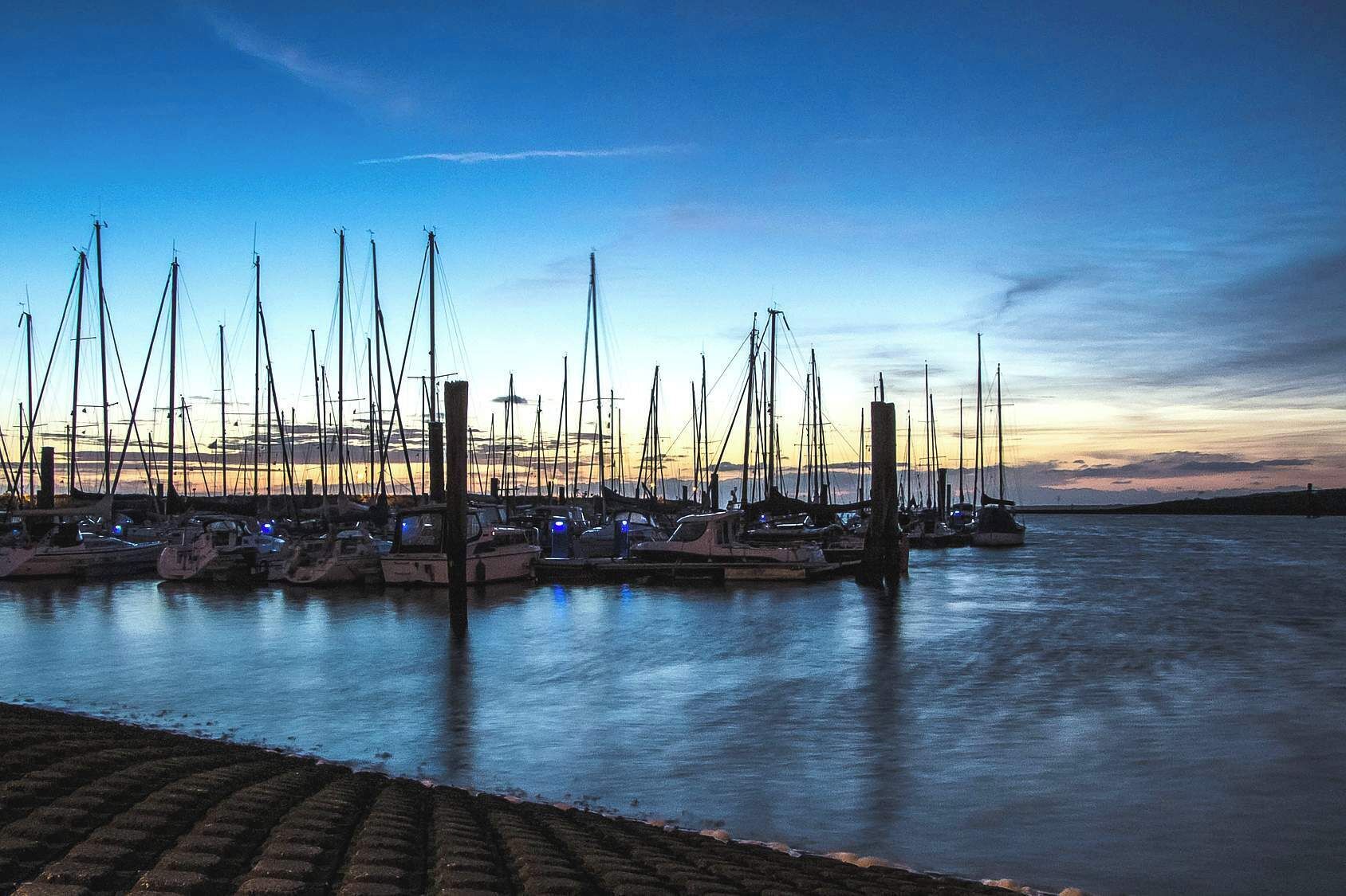 A marina with multiple boats docked at wooden piers.
