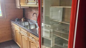 A kitchen with wooden cabinets, a stainless steel sink, and a red refrigerator.