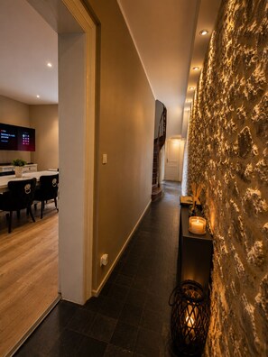 A modern interior with a stone wall, a dining area with chairs, and a staircase. - Villa Margarita – Charming House Facing the Historic Ramparts | Opal Coast (Boulogne-sur-Mer)