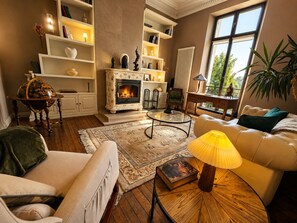 Uma sala de estar aconchegante com lareira, sofá, mesa de centro e estante de livros.