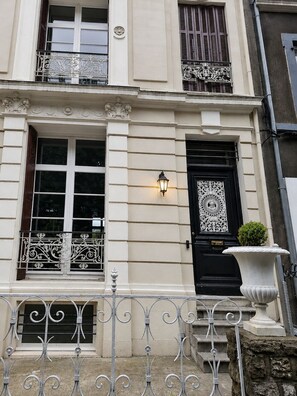 Un bâtiment doté d’une porte noire, de cadres de fenêtres blancs et de balcons en fer forgé décoratifs.