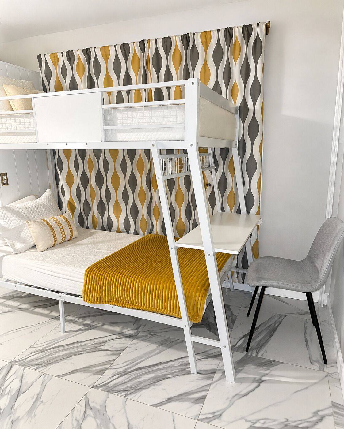 Un letto a castello con testiera e una sedia, una tenda decorata e un pavimento in marmo.