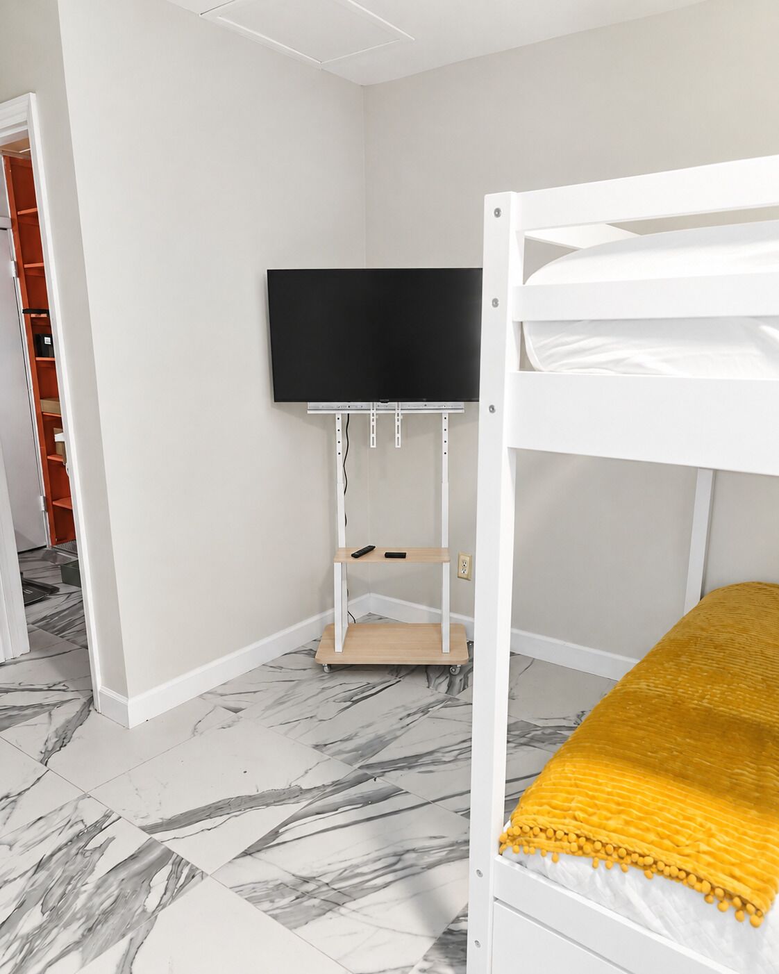 Een kamer met een stapelbed, een wandtelevisie en een wandplank.