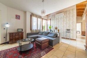 Ein Wohnzimmer mit Sofa, Hocker, Couchtisch und einem gemusterten Teppich.