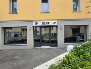 Un edificio con fachada amarilla, un letrero que dice 'REGINA' y dos ventanas grandes.