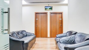 A hallway with two wooden doors, each marked with a number. There are two leather sofas on either side of the hallway. - Super Collection O Pashan-Sus Road Baner (Pune)