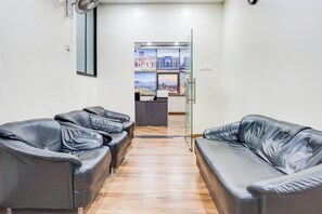 A reception area with two leather sofas, a reception desk, and a view through a glass door. - Super Collection O Pashan-Sus Road Baner (Pune)