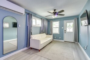 Ein Zimmer mit einem weißen Sofa, einem Deckenventilator, einem großen Spiegel und einer Tür mit Fenster.