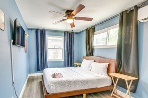 A bedroom with a bed, a ceiling fan, a bedside table, a window, and curtains. - Houston Group Stay! 2 Homes Near Museum District (Houston)