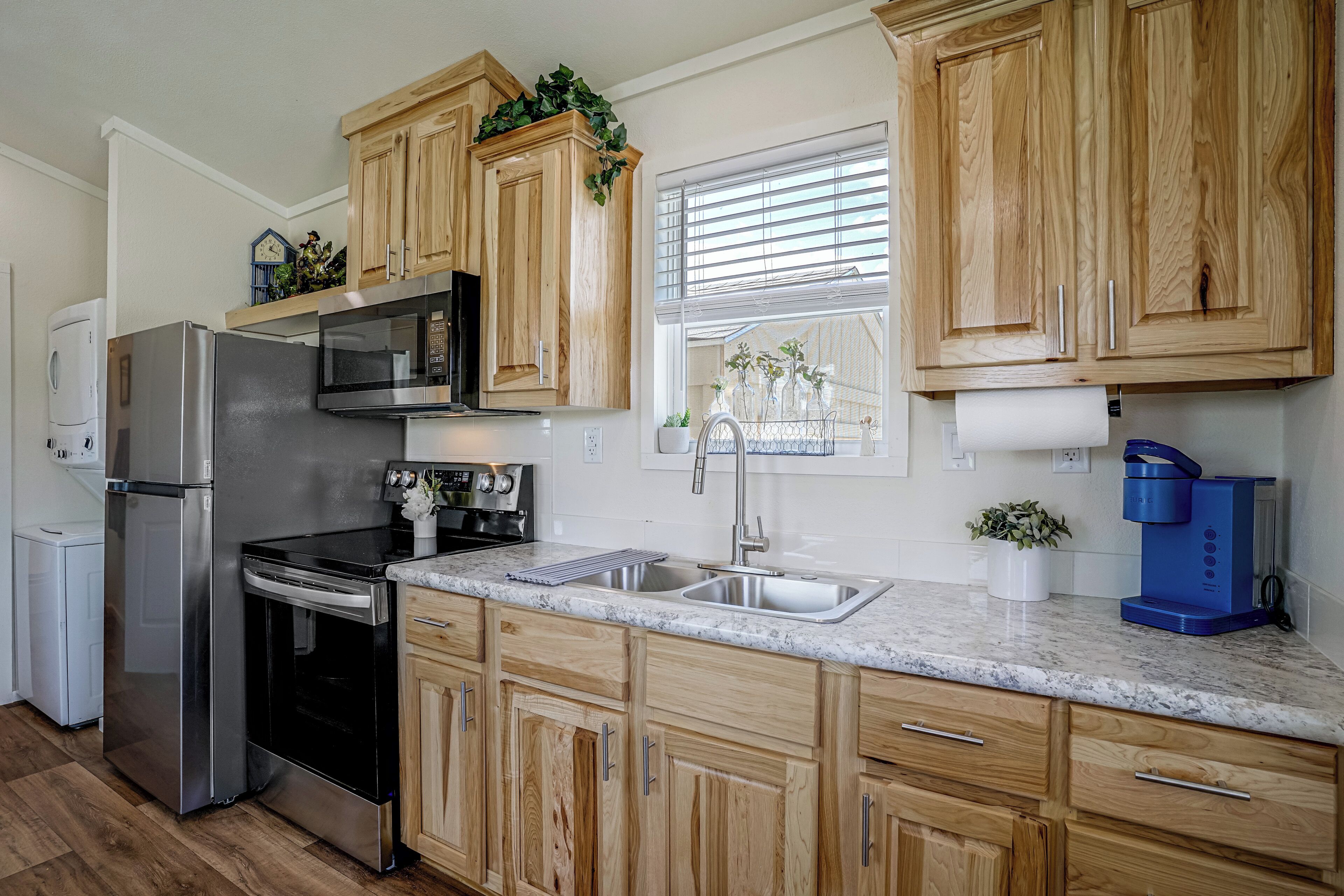 A modern kitchen with wooden cabinets, stainless steel appliances, and a marble countertop.