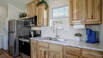 A modern kitchen with wooden cabinets, stainless steel appliances, and a marble countertop.