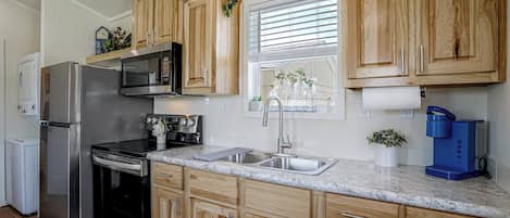 A modern kitchen with wooden cabinets, stainless steel appliances, and a marble countertop.