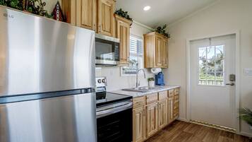 A modern kitchen with stainless steel appliances, wooden cabinets, and a window with a view.