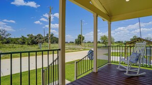 A wooden porch with a view of a road and greenery. - Tiny Home Retreat Close to Lake Granbury (Granbury)
