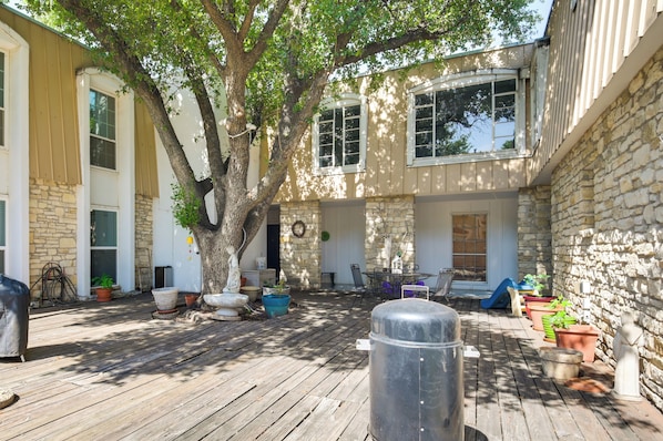 A covered outdoor patio with a wooden deck, stone walls, and potted plants.
