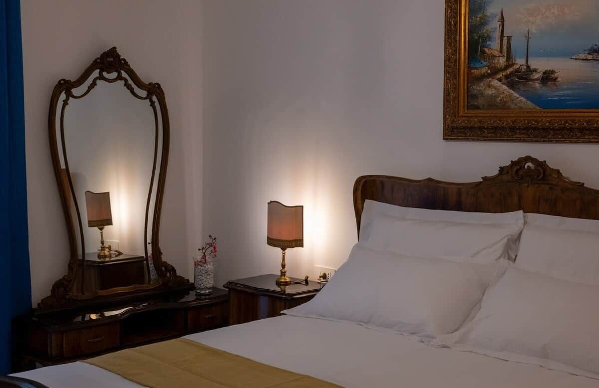 Une chambre d’hôtel avec un grand lit, deux tables de chevet, un miroir, un tableau et une lampe.