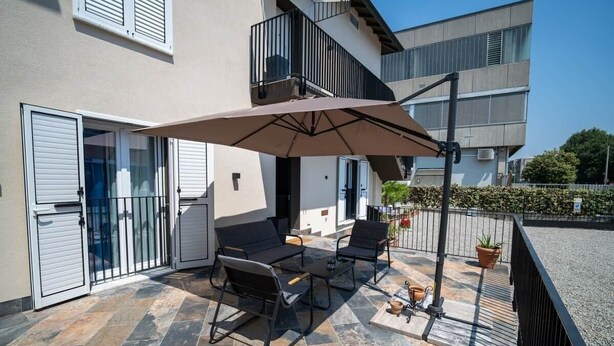 An outdoor patio with a table and chairs, a large umbrella, and a potted plant. - "Matilda Airport BG-4 -minute drive from BGY" (Bergamo)