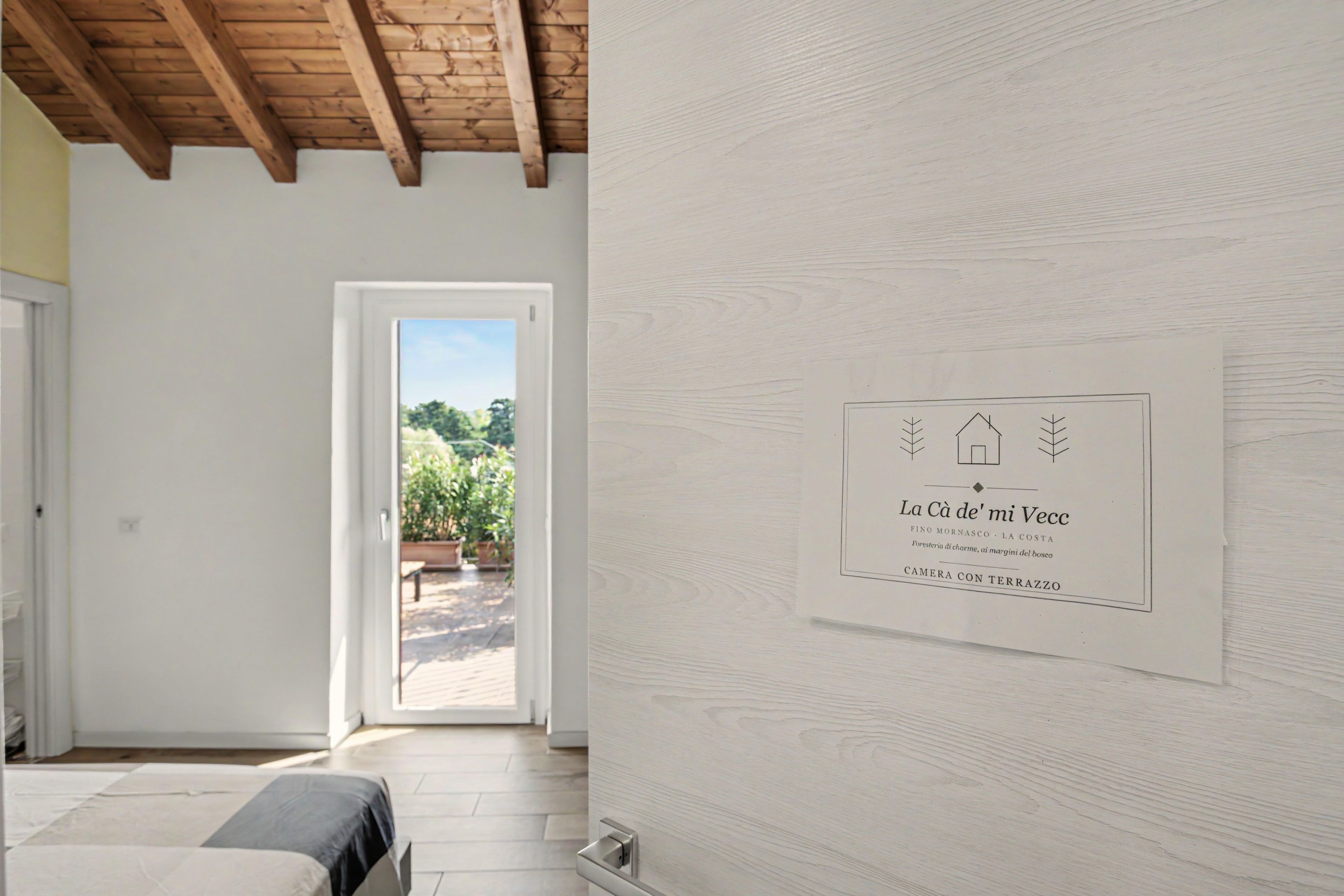 Une pièce avec un plafond en bois, une porte donnant sur l’extérieur et une enseigne fixée au mur avec du texte.