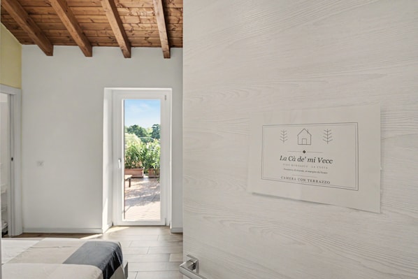 A room with a wooden ceiling, a door leading outside, and a wall-mounted sign with text.