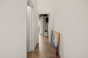 A hallway with wooden flooring, white walls, and a painting on the right. - Room with Terrace at 'La Cà De' Mi Vecc' – Private Terrace & Wi-Fi (Costa)