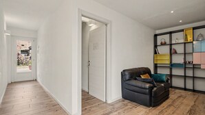 A modern interior with a leather sofa, a wooden floor, and a built-in bookshelf with various items.