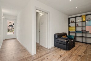 A modern interior with a leather sofa, a wooden floor, and a built-in bookshelf with various items.