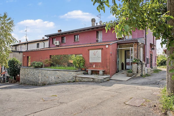 A building with a red facade, a stone wall in front, and a sign indicating a restaurant.
