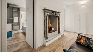 Una sala de estar moderna con chimenea, piso de madera y un sofá con un cojín decorativo.
