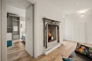 A modern living room with a fireplace, wooden flooring, and a sofa with a decorative pillow.