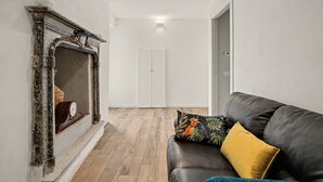 Una habitación con chimenea, un sofá con cojines y suelo de madera.
