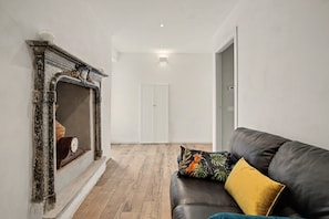 A room with a fireplace, a sofa with cushions, and a wooden floor.