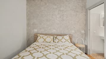 A bedroom with a bed, a bedside table, and a door leading to a bathroom.