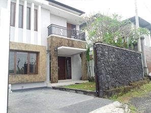 A modern two-story house with a stone facade, a balcony, and a small front yard. - Saren Kayutulang, Quiet 3BR Pool Villa (Badung)