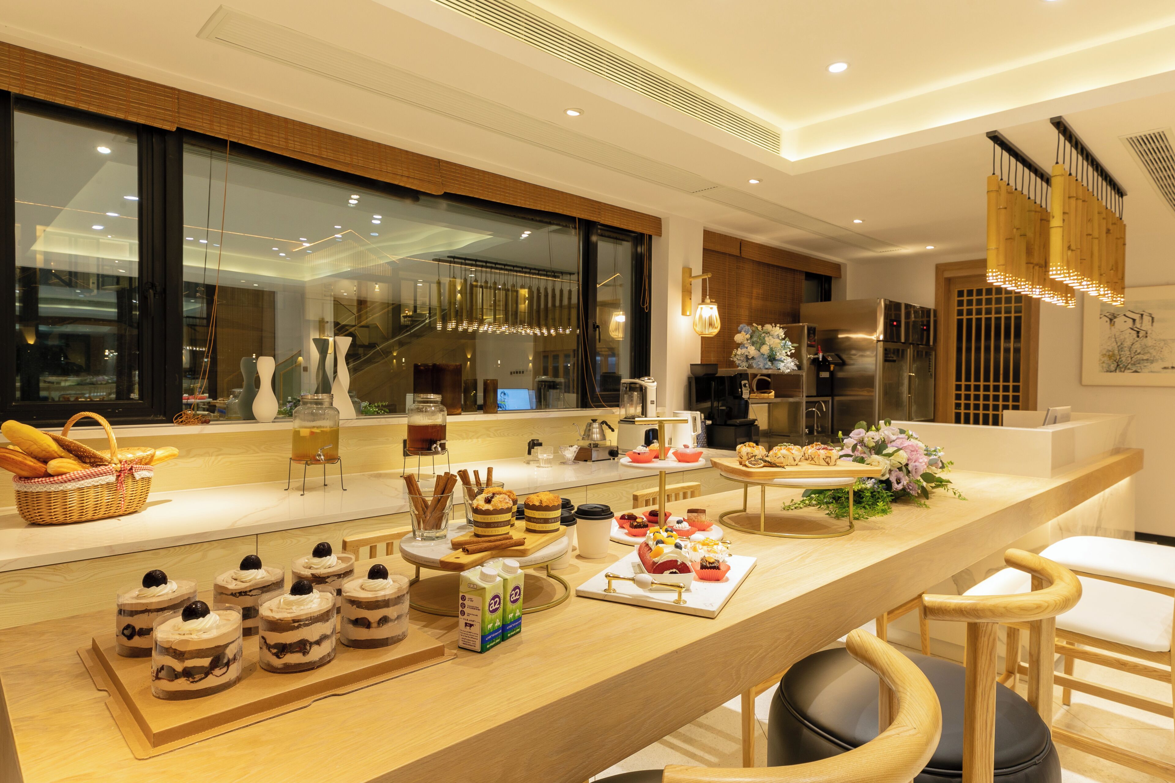 A modern kitchen with a long counter displaying various desserts and a coffee station.