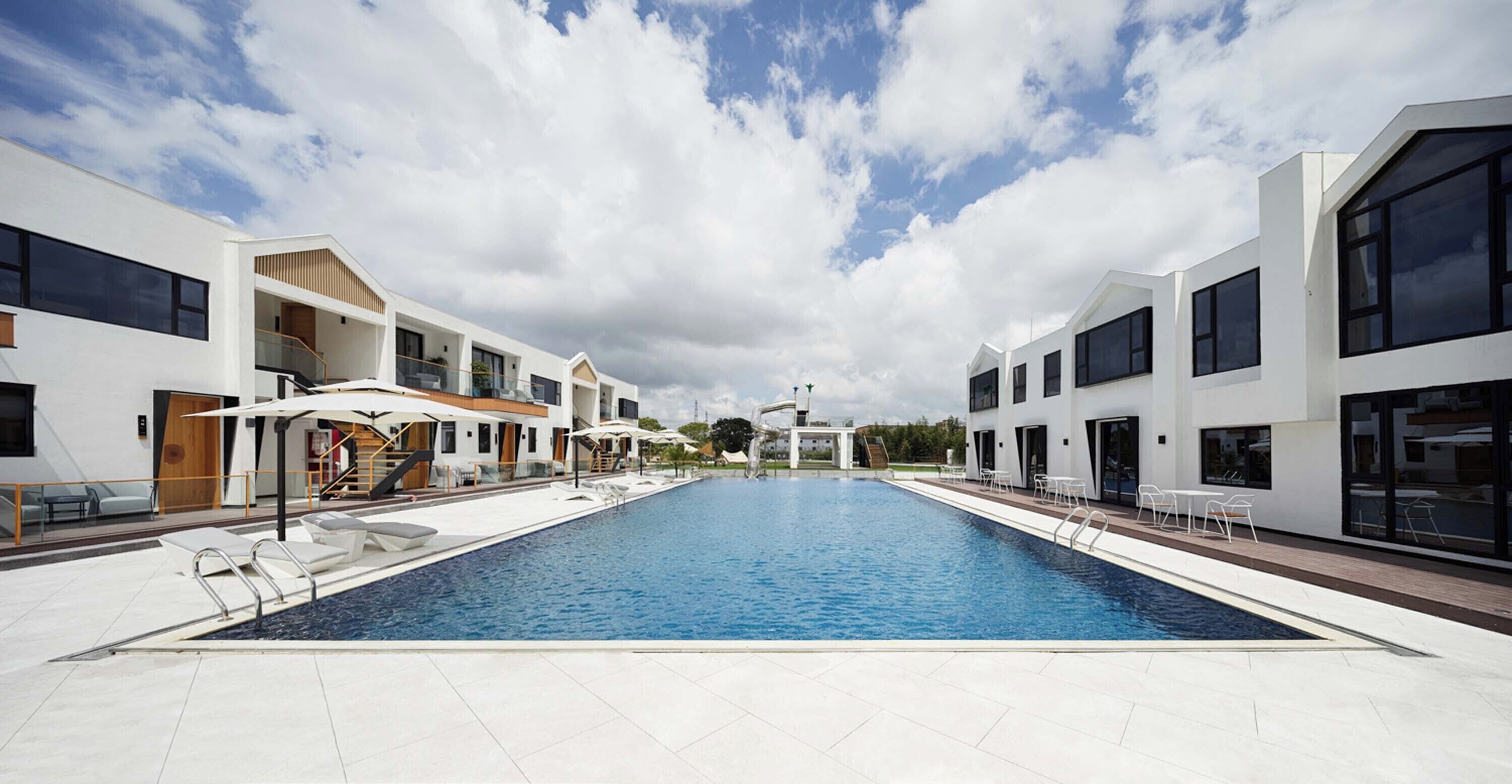Un hotel moderno con una piscina centrale, numerosi balconi e zone relax all'aperto.