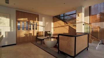 A modern interior with a staircase, a seating area with a round table, and a large window.