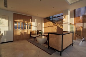 Un intérieur moderne avec un escalier, un coin salon doté d’une table ronde et une grande fenêtre.