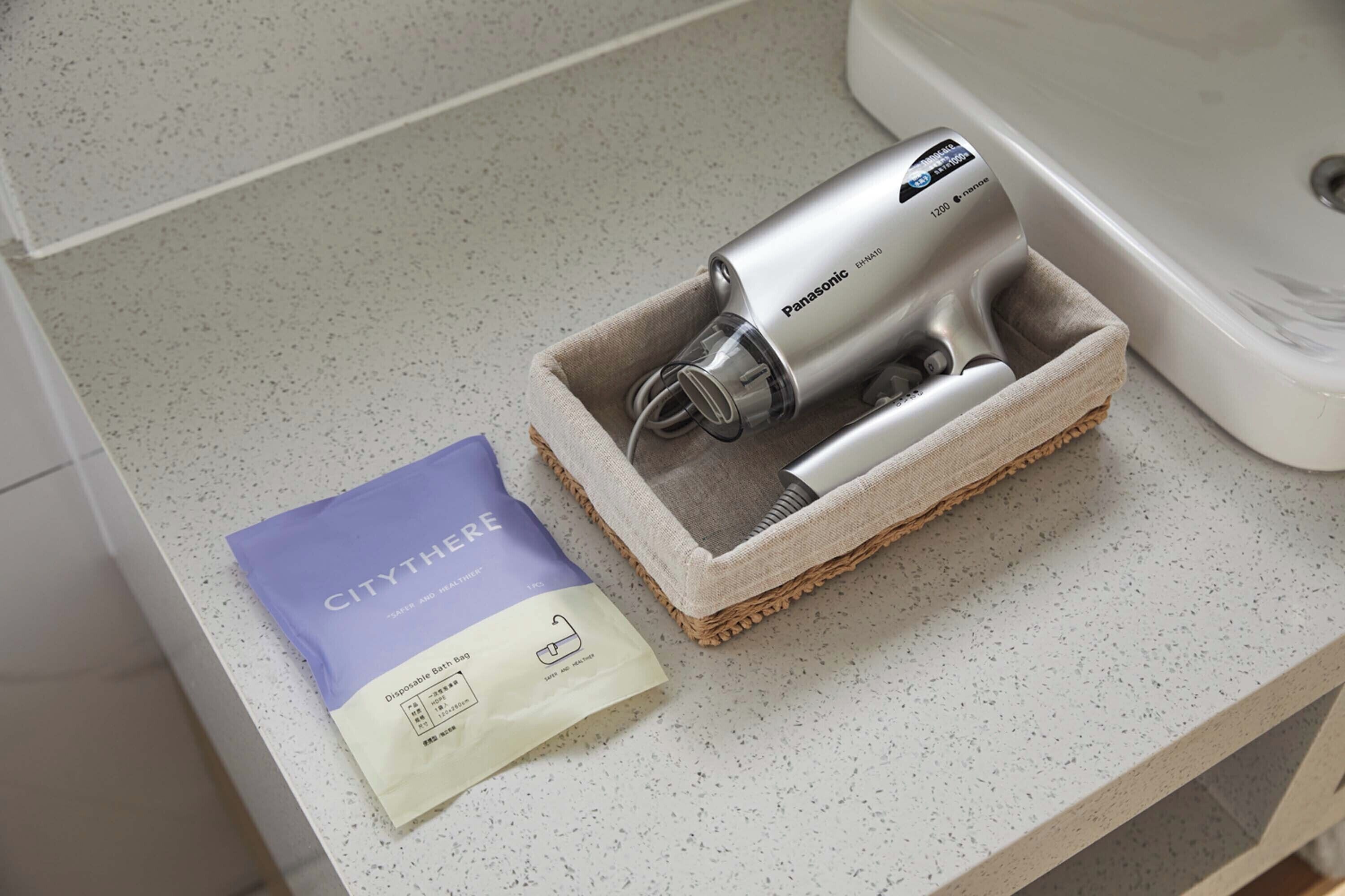 A Panasonic hair dryer in a woven basket on a countertop, next to a purple and white package labeled 'CITYTHERE'.