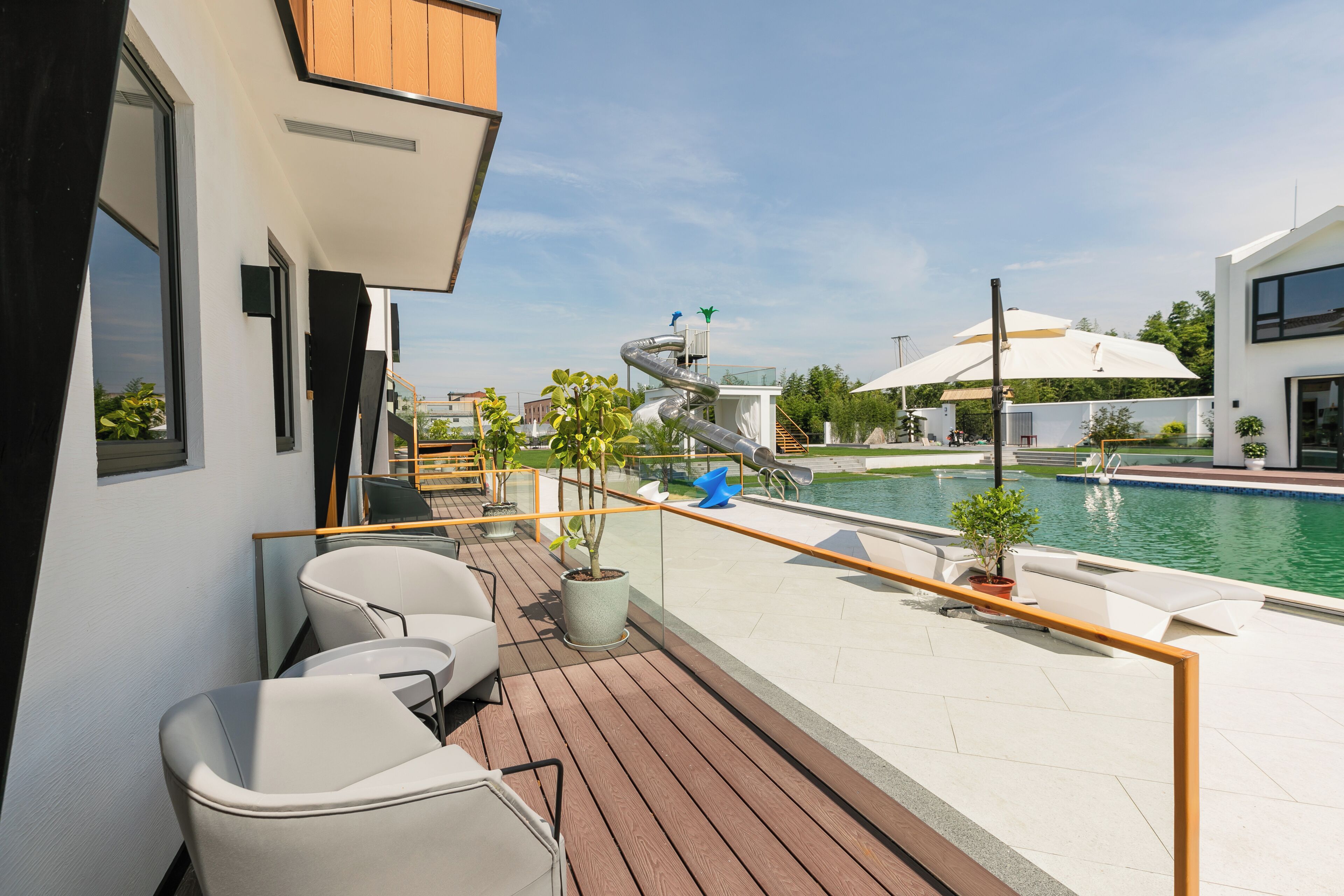 Ein Balkon mit Pool, Sitzgelegenheiten im Freien und einer Rutsche.