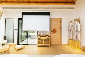 Una habitación moderna con una pantalla grande, muebles de madera, una bañera y un perchero.